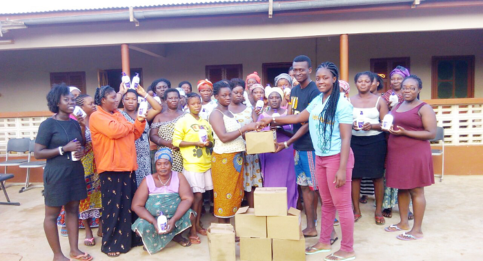 Nii Aryee Tagoe , president of the association, and his vice president, Portia Buernarkie Nartey, presenting boxes of body lotion to some women in the community